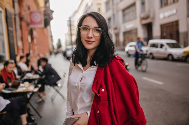 Mujer alegre con sonrisa cansada posando en la muralla de la ciudad