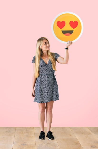 Foto gratuita mujer alegre sosteniendo un emoticon de ojos de corazón