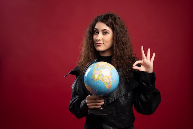 Mujer alegre sosteniendo globo y dando señal ok.