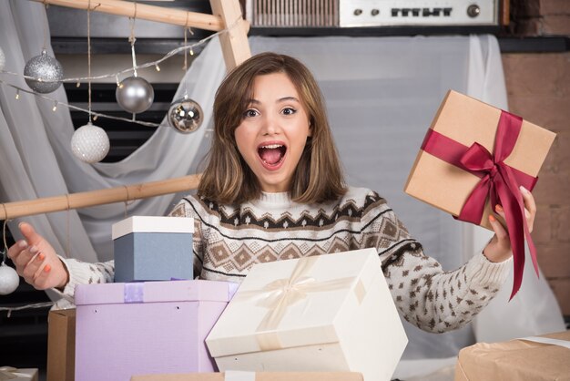 Mujer alegre sosteniendo un regalo de Navidad en la sala de estar.