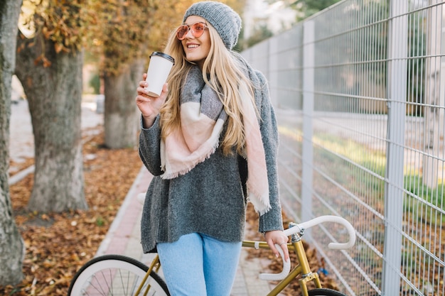 Mujer alegre con taza y bicicleta