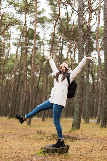 Mujer alegre en tocón en el bosque