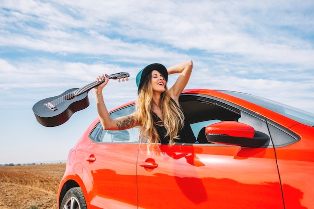 Mujer alegre con ukelele en coche