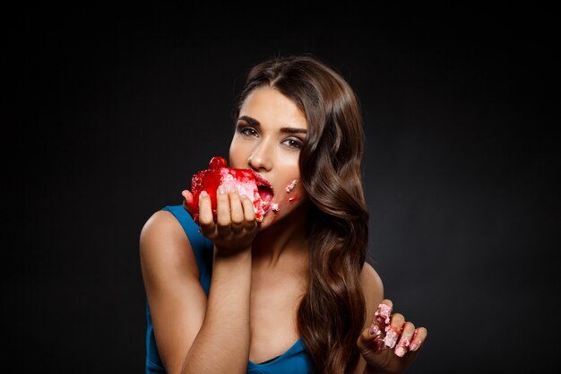 Mujer alegre en vestido azul comiendo pastel