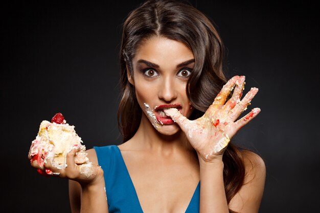 Mujer alegre en vestido azul comiendo pastel