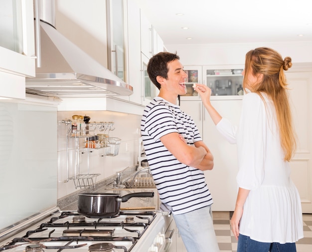 Mujer alimentando palomitas a su esposo en la cocina