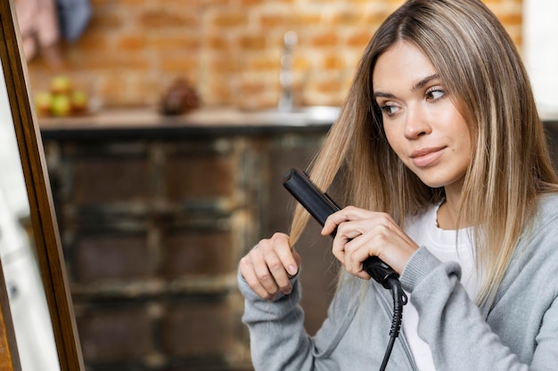 Mujer alisándose el cabello en casa