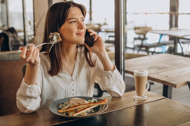 Mujer almorzando en un café, comiendo ensalada