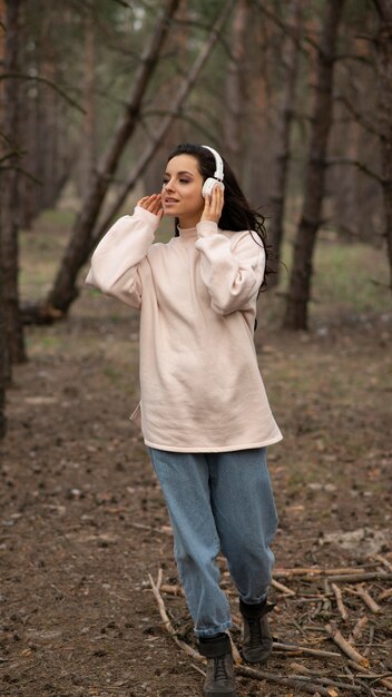 Mujer de alto ángulo con auriculares en la naturaleza