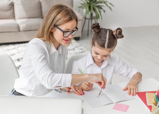 Mujer de alto ángulo ayudando a su hija con la tarea