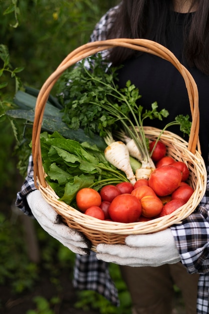 Mujer de alto ángulo con cesta de tomates