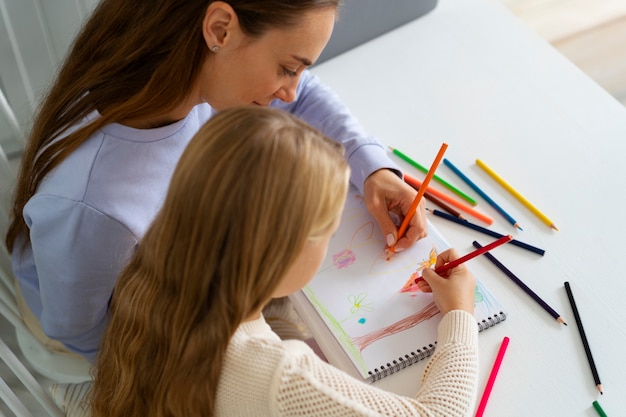 Foto gratuita mujer de alto ángulo para colorear con niña