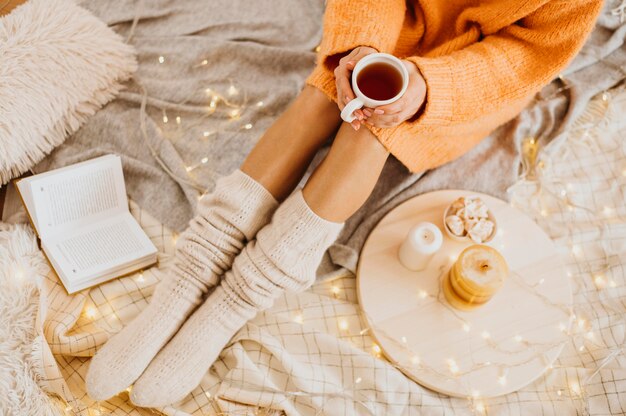 Mujer de alto ángulo disfrutando de las vacaciones de invierno con una taza de té