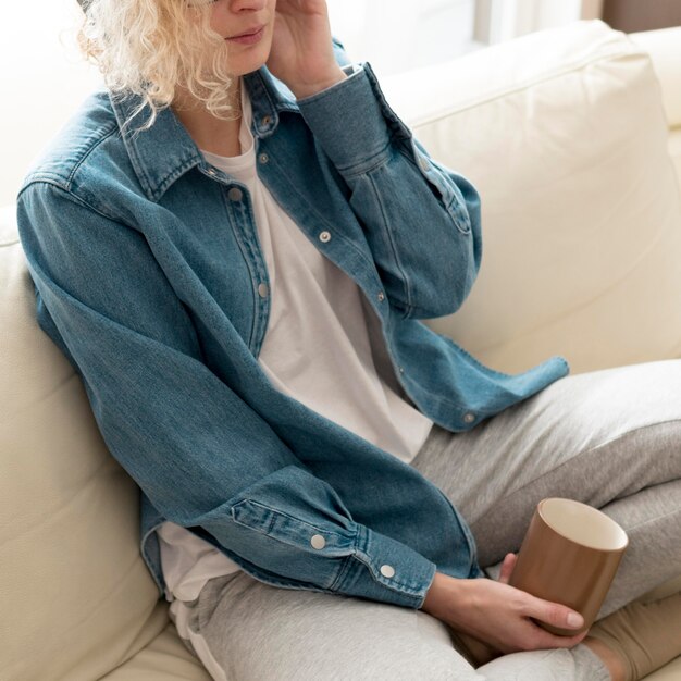 Mujer de alto ángulo escuchando música y sosteniendo la taza de café