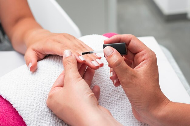 Mujer de alto ángulo haciendo la manicura de un cliente