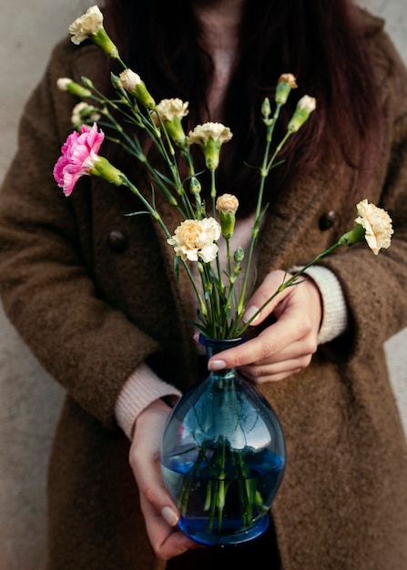 Mujer de alto ángulo con jarrón con flores