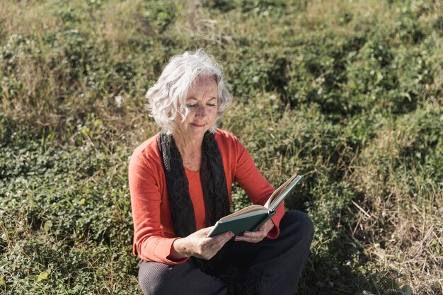 Mujer de alto ángulo leyendo al aire libre