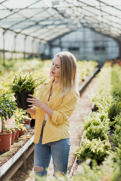 Mujer de alto ángulo con maceta con planta