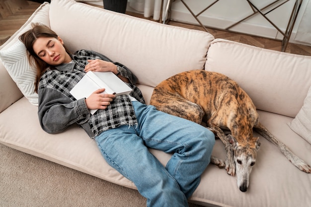 Mujer de alto ángulo y perro durmiendo en el sofá