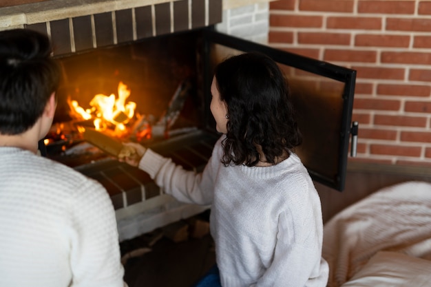 Foto gratuita mujer de alto ángulo poniendo leña en la chimenea