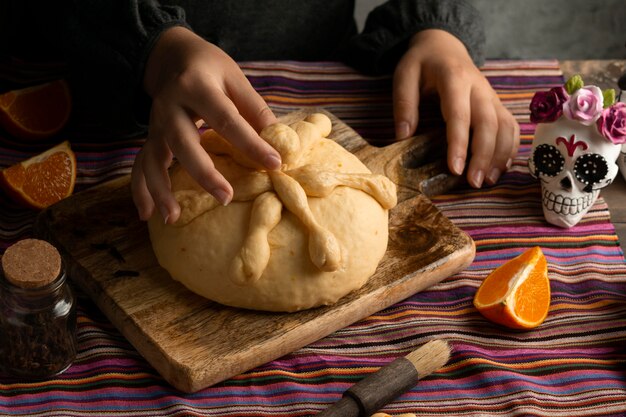 Mujer de alto ángulo preparando masa de pan de muerto