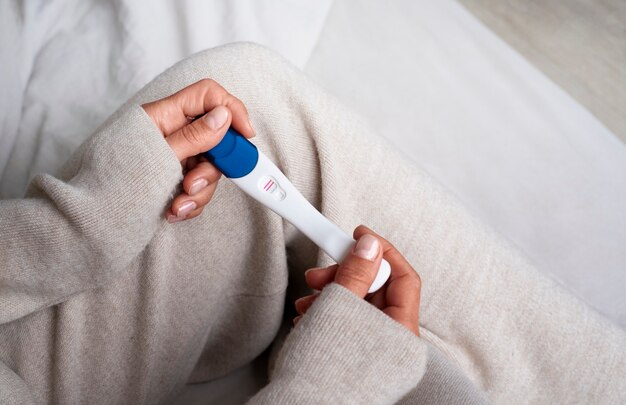 Mujer de alto ángulo con pruebas de embarazo positivas