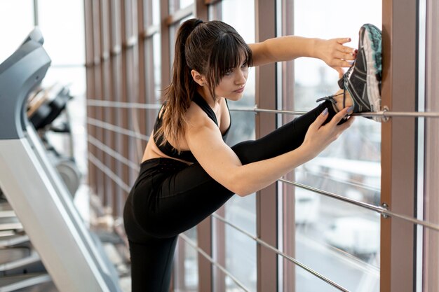 Mujer de alto ángulo que se extiende en el gimnasio