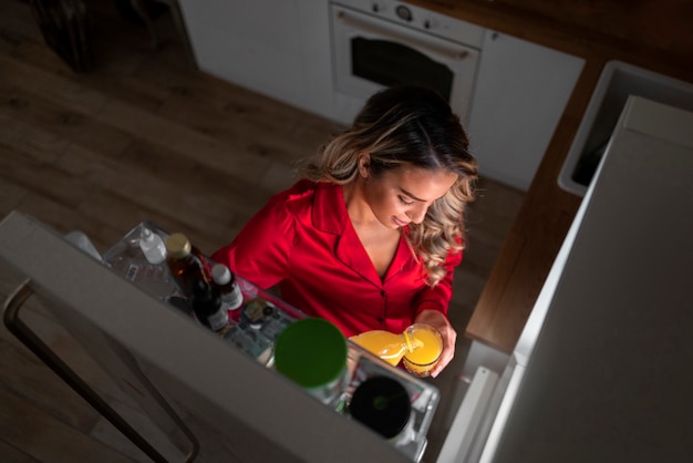 Foto gratuita mujer de alto ángulo revisando el refrigerador por la noche