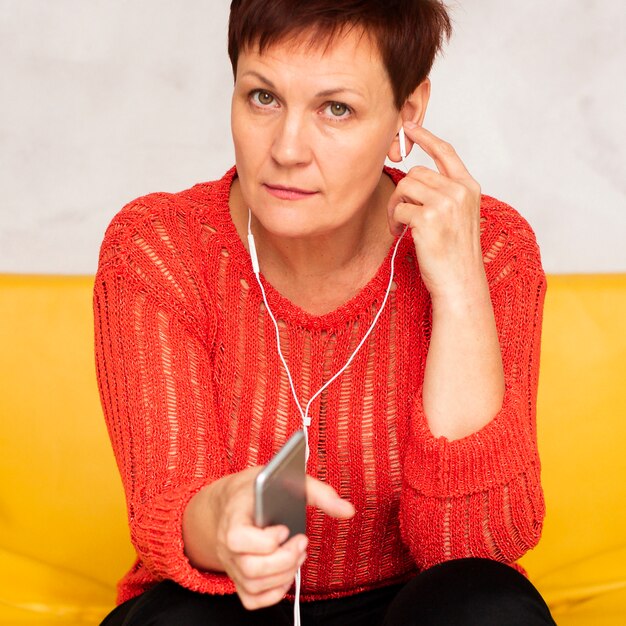 Mujer de alto ángulo en el sofá escuchando música