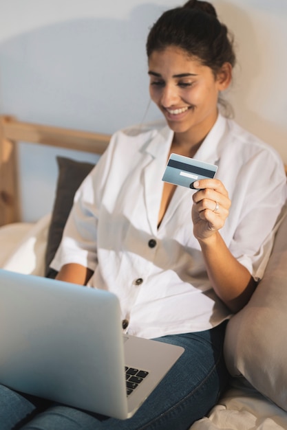 Mujer de alto ángulo sosteniendo una tarjeta y trabajando en la computadora portátil