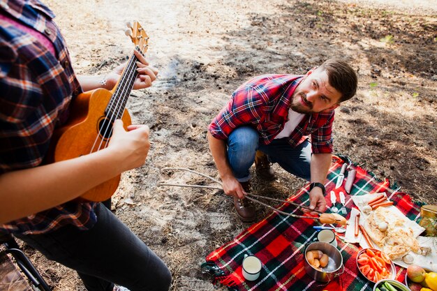 Mujer de alto ángulo tocando instrumento y hombre cocinando