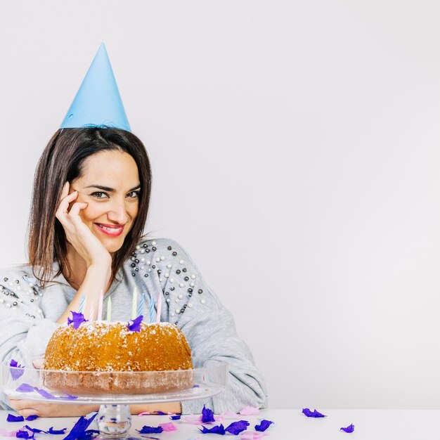 Mujer amable detrás de tarta de cumpleaños