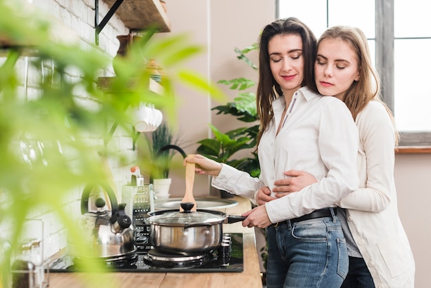 Mujer amando a su novia cocinando en la cocina