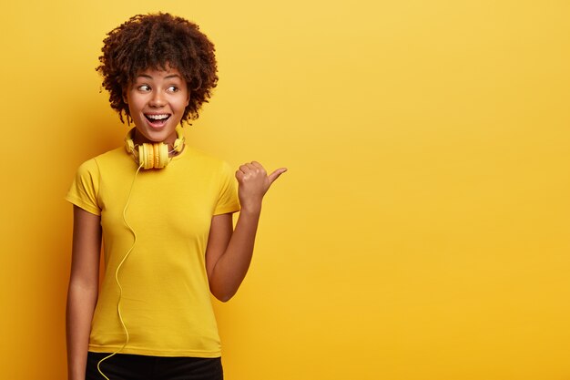 Mujer americana africana, llevando, camiseta amarilla, y, auriculares
