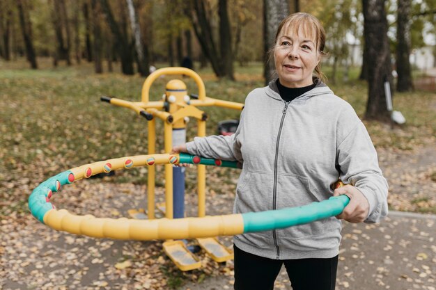 Mujer anciana sonriente fuera trabajando con equipo