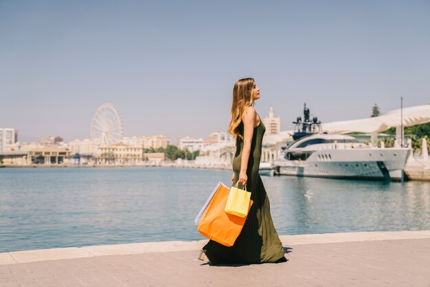 Mujer andando con bolsas de compras al lado del mar