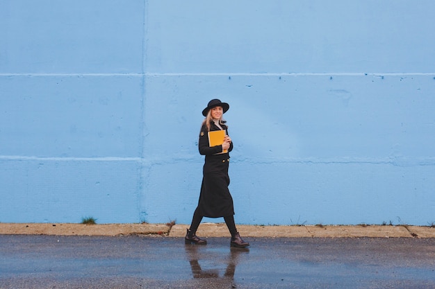 Mujer andando enfrente de un muro azul