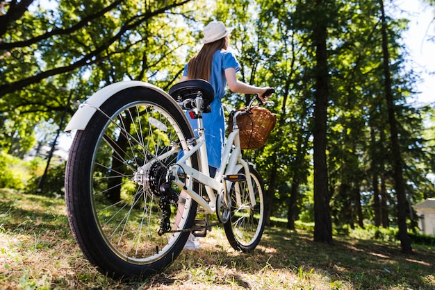 Foto gratuita mujer de ángulo bajo caminando con bicicleta