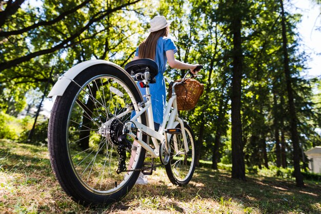 Mujer de ángulo bajo caminando con bicicleta