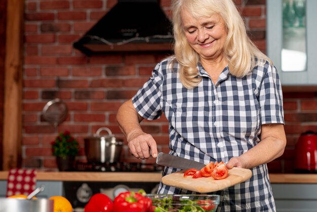 Mujer de ángulo bajo, cocinar alimentos saludables