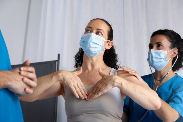 Mujer de ángulo bajo y enfermera con máscaras