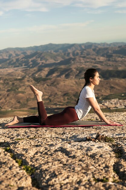 Mujer de ángulo bajo en el entrenamiento de yoga mat