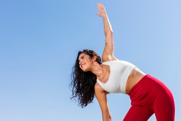 Foto gratuita mujer de ángulo bajo estirando al aire libre