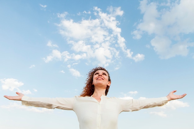 Mujer de ángulo bajo feliz de estar en la naturaleza