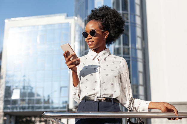 Foto gratuita mujer de ángulo bajo con gafas de sol y teléfono