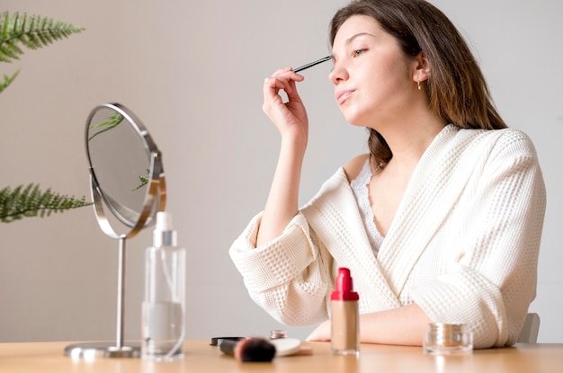 Mujer de ángulo bajo haciendo sus cejas