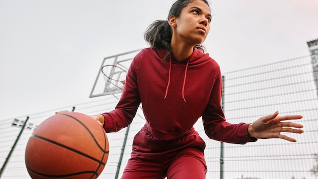 Foto gratuita mujer de ángulo bajo jugando baloncesto