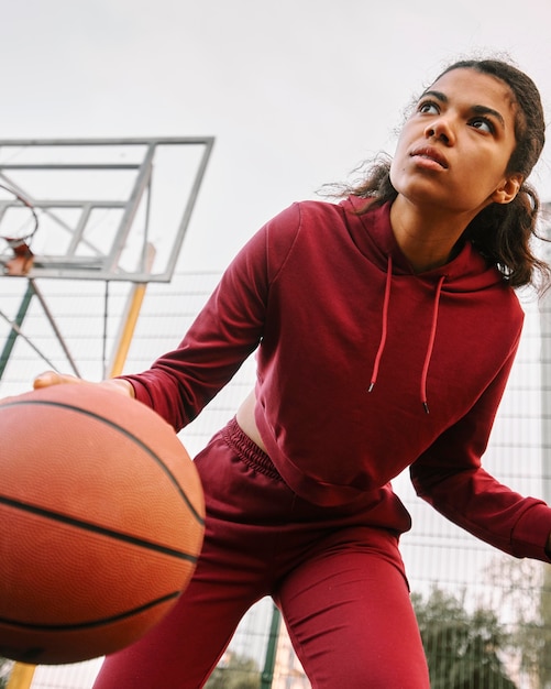 Foto gratuita mujer de ángulo bajo jugando baloncesto