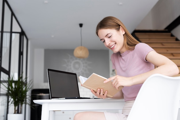 Foto gratuita mujer de ángulo bajo leyendo su libro