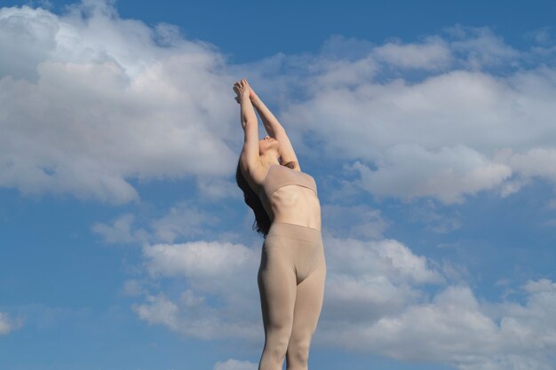 Mujer de ángulo bajo meditando afuera